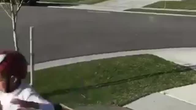 White shirt helmet kid rides bike off ramp screams on sidewalk