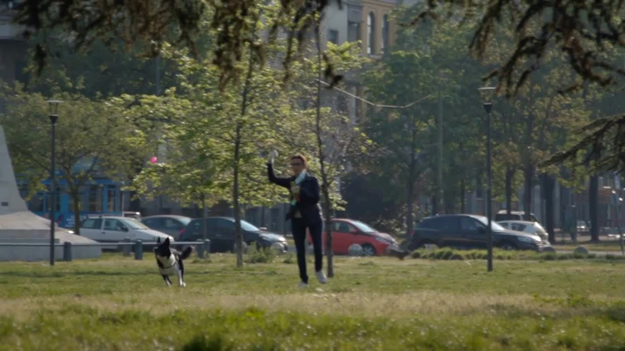 Italian Woman Playing With Her Dog Pet In Park Of Milan, Italy