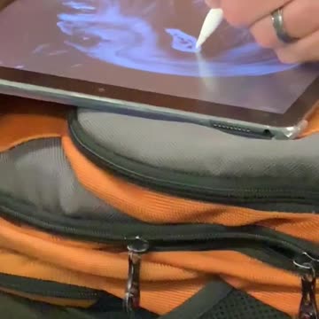 Man in orange sweater drawing on tablet on train subway