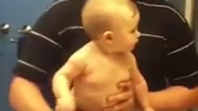 Baby adorably flexes muscles with dad ok