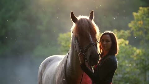 Girl hugs the horse, she tries to calm her down, on the background of a beautiful forest