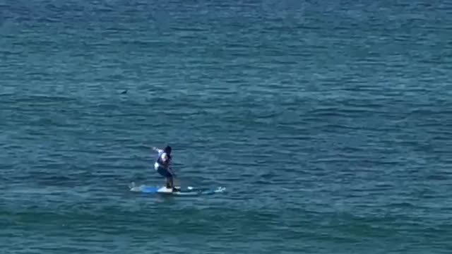 Guy tries to stand on a surfboard and he falls off