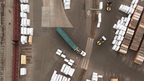 A Cargo Truck Maneuvering Turns In A manufacturing Plant drone shot