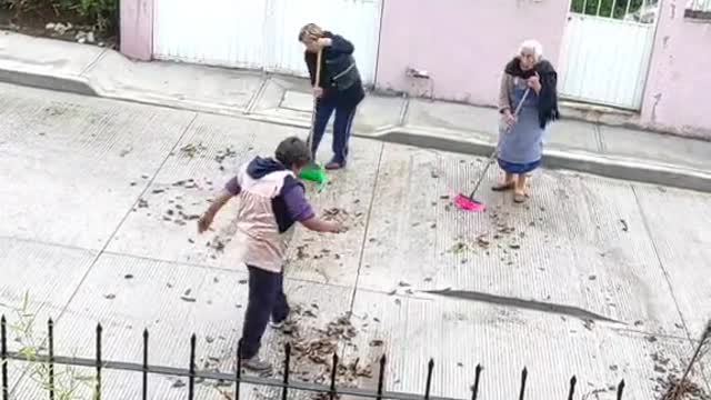 Las vecinas barriendo la tierra para el frente de mi casa