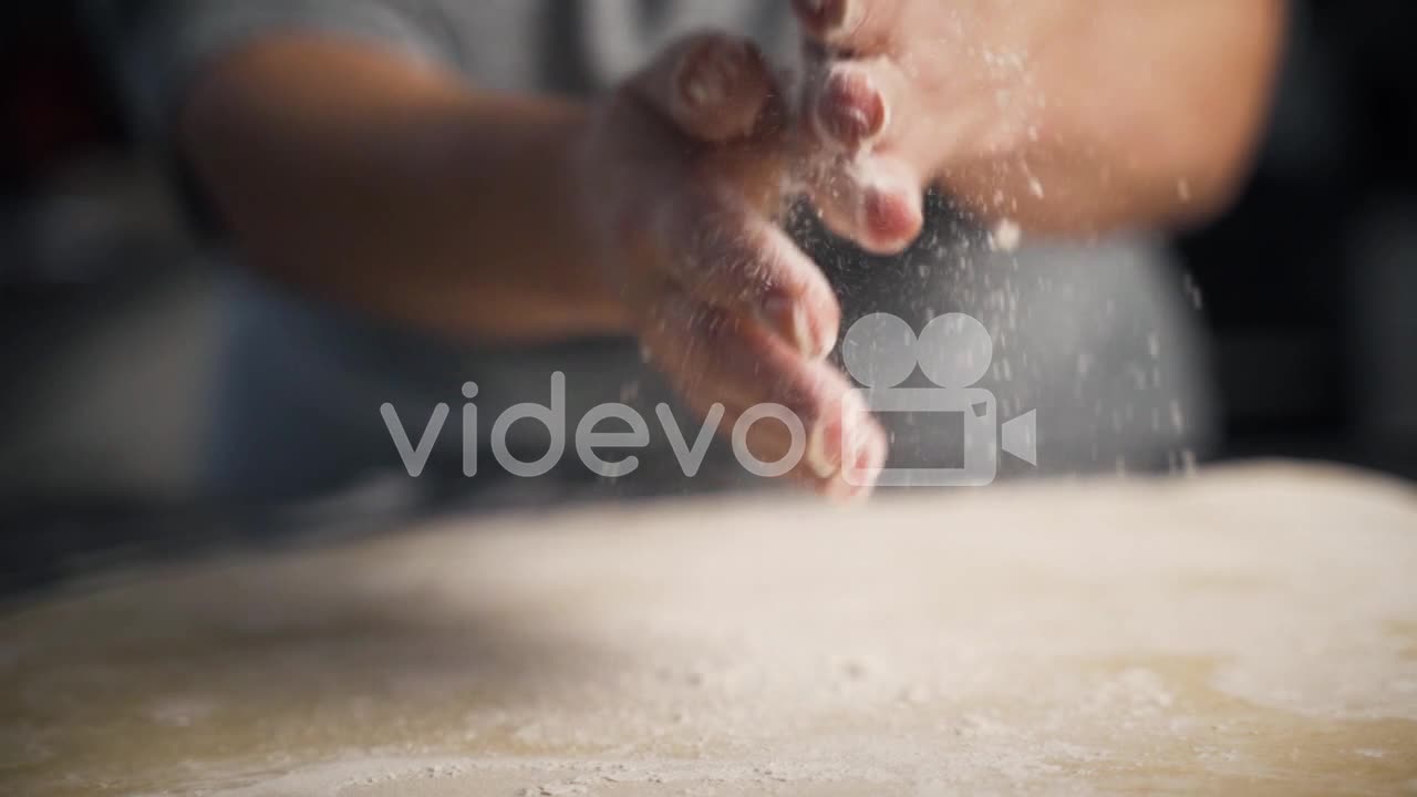 Close up, slow motion view of woman's hands wiping off flour after working with pastry dough