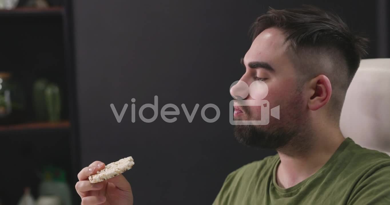 Hungry Man Sitting At Desk And Eating A Rice Cracker