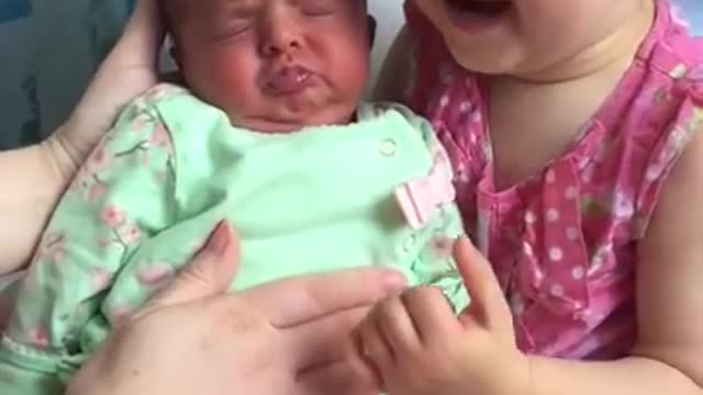 Cute toddler holds baby sister for the first time