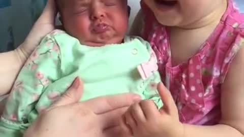 Cute toddler holds baby sister for the first time