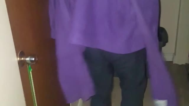 Guy walks with purple jacket on and bumps picture on a wall