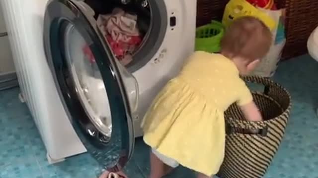 Baby adorably helps her mom with the laundry!