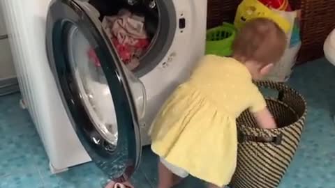 Baby adorably helps her mom with the laundry!