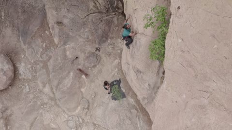 Alpinist climbing a mountain in aerial view