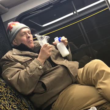 Man eats nuts out of bad and drinks milk on subway train