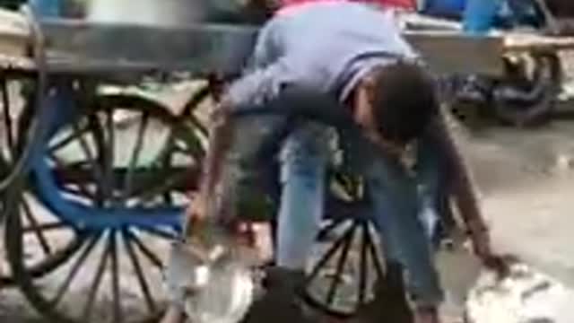 Guy washing plates in dirty water in India at food stall