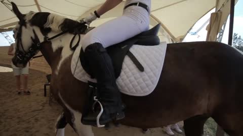 A young female jockey rides a horse through a group of spectators at the entrance