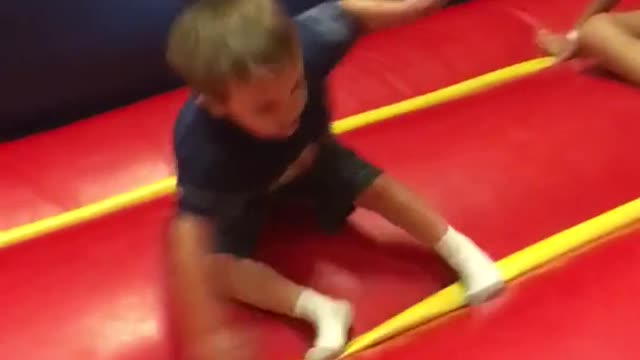 Kid spins in circle and falls over in red and blue bouncy house