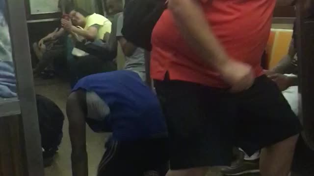 Guy in blue dances in between man in orange legs