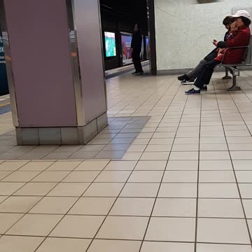 Man in black waving arms around in subway station