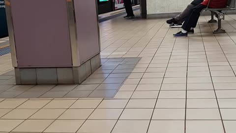 Man in black waving arms around in subway station