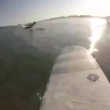Guy on surfboard gets hit by wave and falls in water