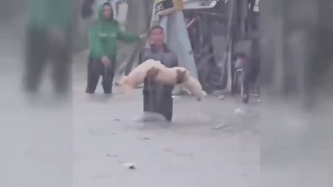 Palestinian boy carrying the lifeless body of a child