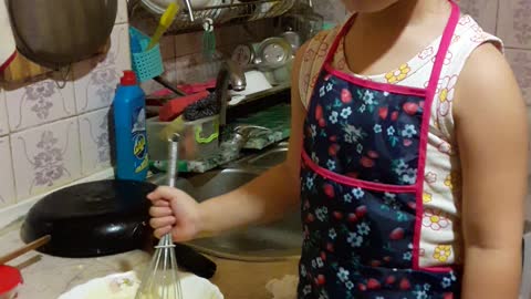 The little girl is very interested in baking.