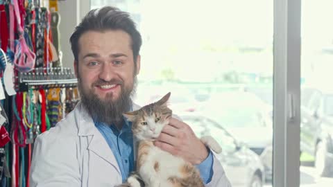 Friendly vet smiling to the camera, holding cute grumpy cat