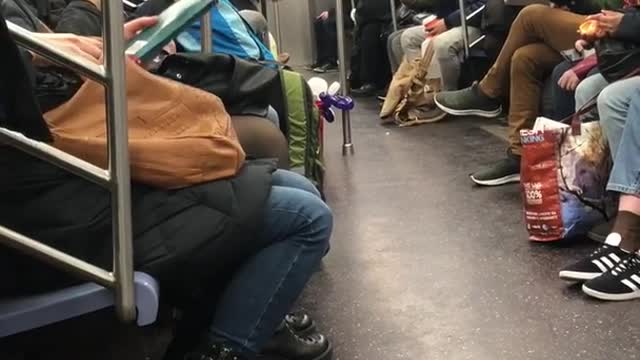 Man makes balloon animal hearts on subway train, gives one to woman recording