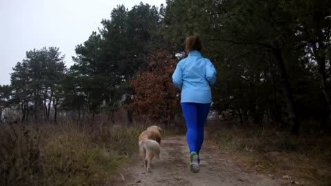 Woman and her dog running down a path