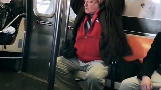 Old man on subway raises his arms up and moves them slowly