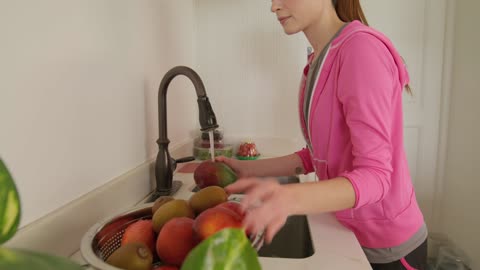 Young woman washing fruit in her kitchen