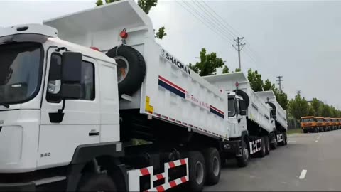 New Dump Trucks Lined Up on the Side of the Road in an Unknown Location