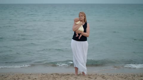 Mother holding her baby alone at the shore