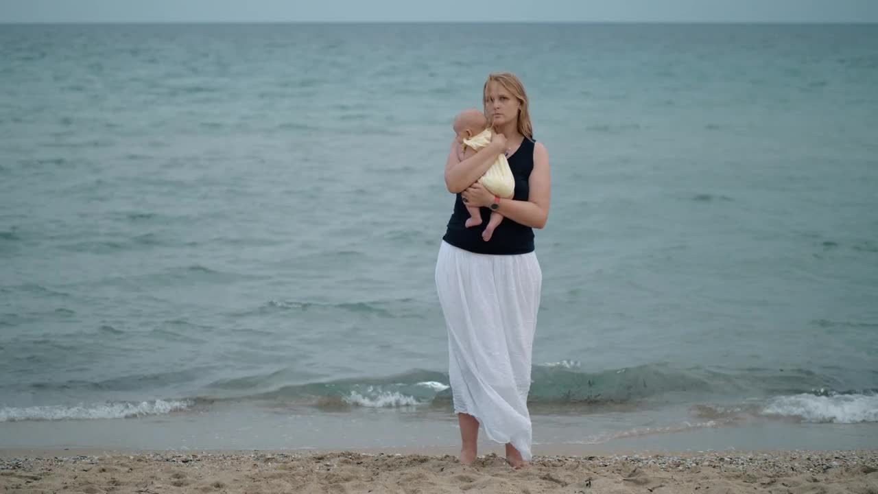 Mother holding her baby alone at the shore