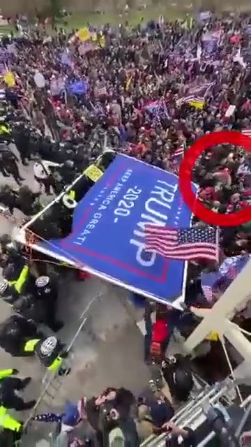 Ray Epps (Ebbs) throwing a Trump sign at the cops.