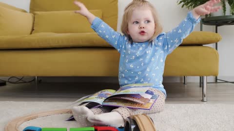 A little girl with A Book flopping her hands