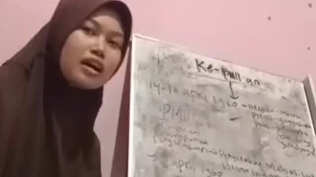Seorang mahasiswi sedang belajar di tempat tidur