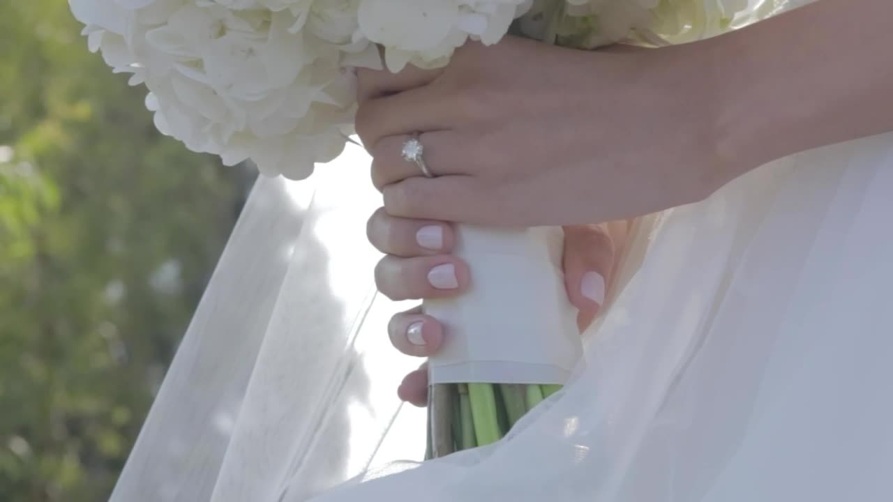 Hands of a bride with the ring and her bouquet