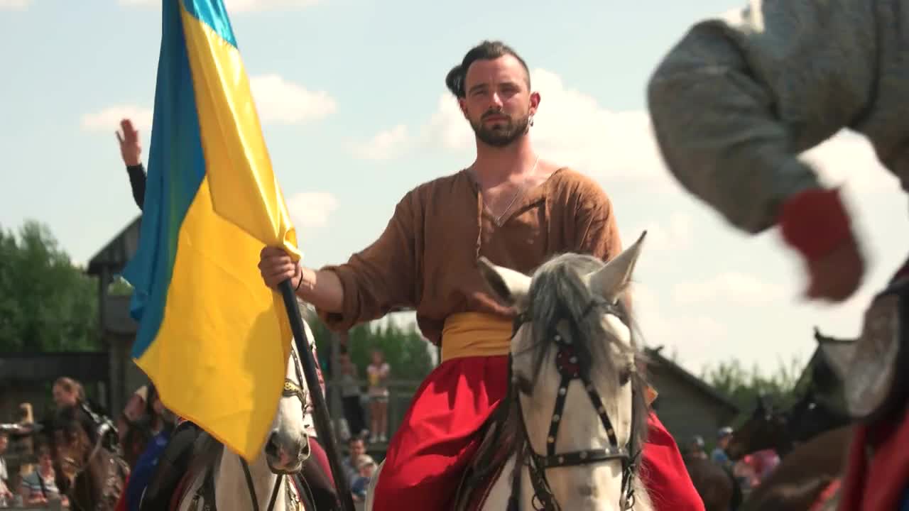 Kopachiv, Ukraine. Women riding horseback on a horse while carrying different flags