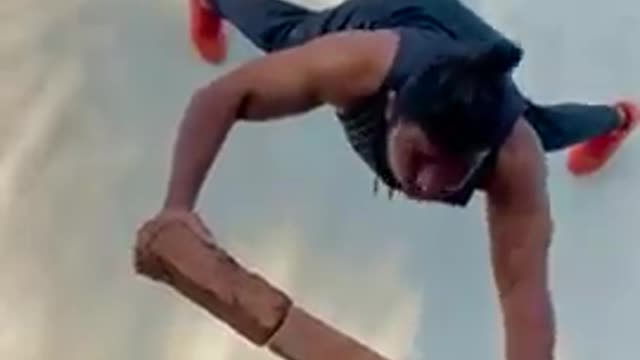 Man Does Push-Ups Against the Wall While Balancing on Three Slanting Bricks