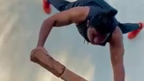 Man Does Push-Ups Against the Wall While Balancing on Three Slanting Bricks