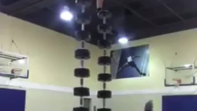 Guy balances on and does a pushup on dumbbell tower