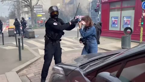 Paris policemen takes away the mask of a woman and gives her a batoon on the feet