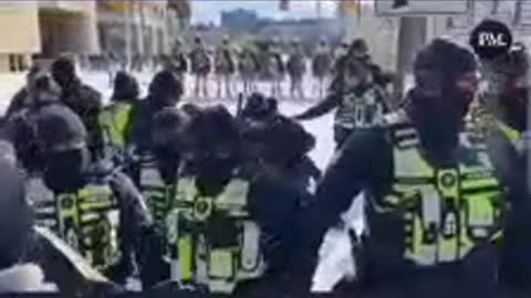 A police officer appears to be hitting someone with the butt of his gun.