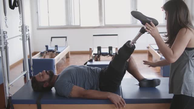 Woman Helping a Man with Prosthetic Legs to Stretch