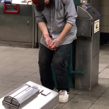 Man in blue hat falling asleep standing up in subway station