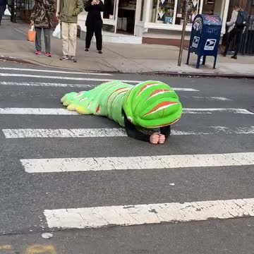 Person crawling on street floor green caterpillar