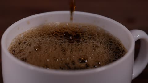 Filling a white cup of coffee