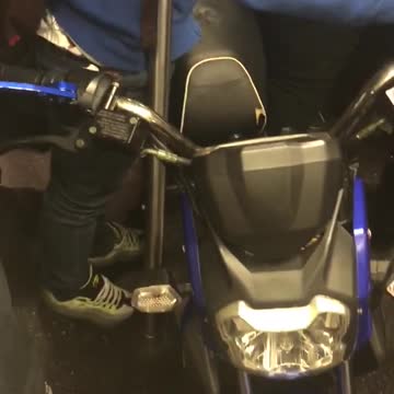 Guy brings blue motorcycle into subway
