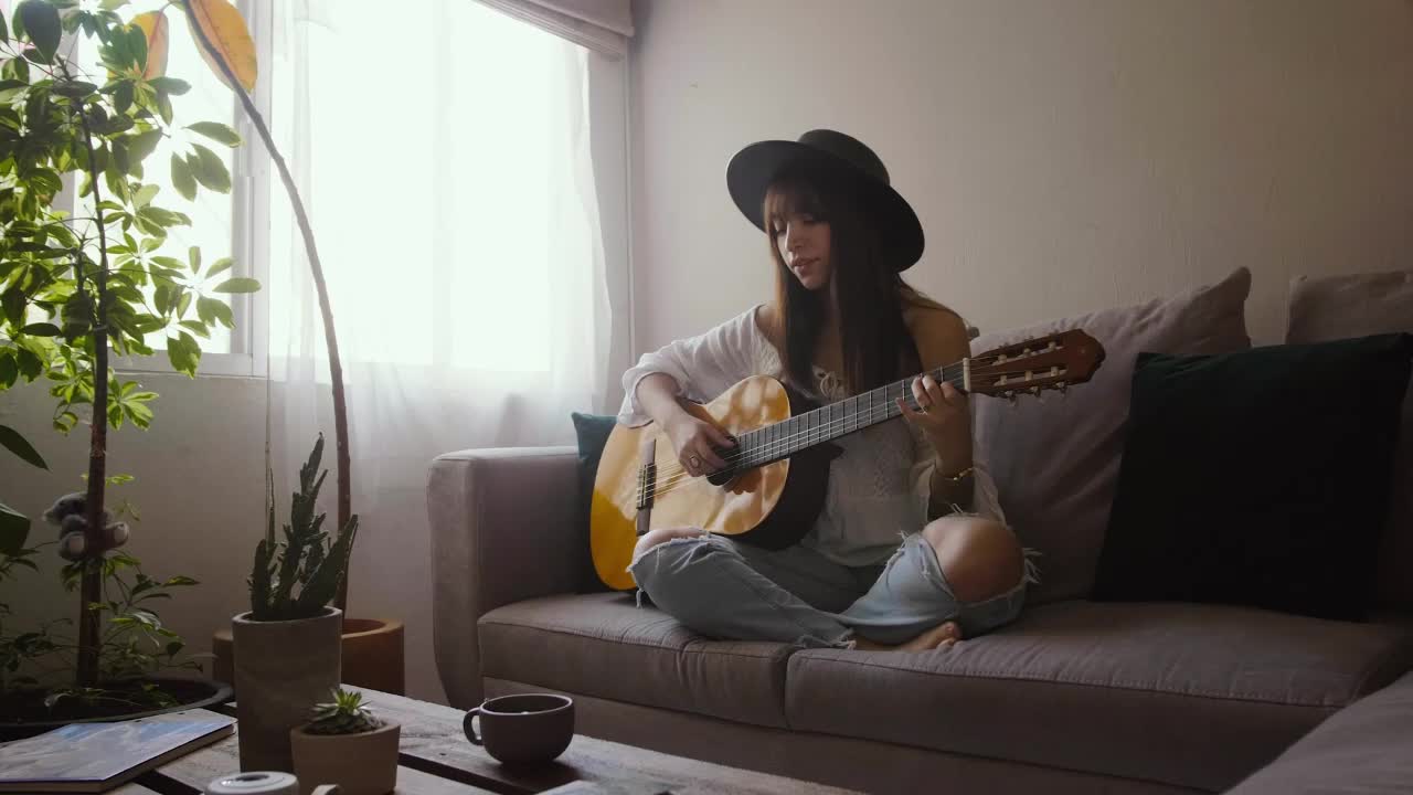 Woman playing an acoustic guitar in her living room